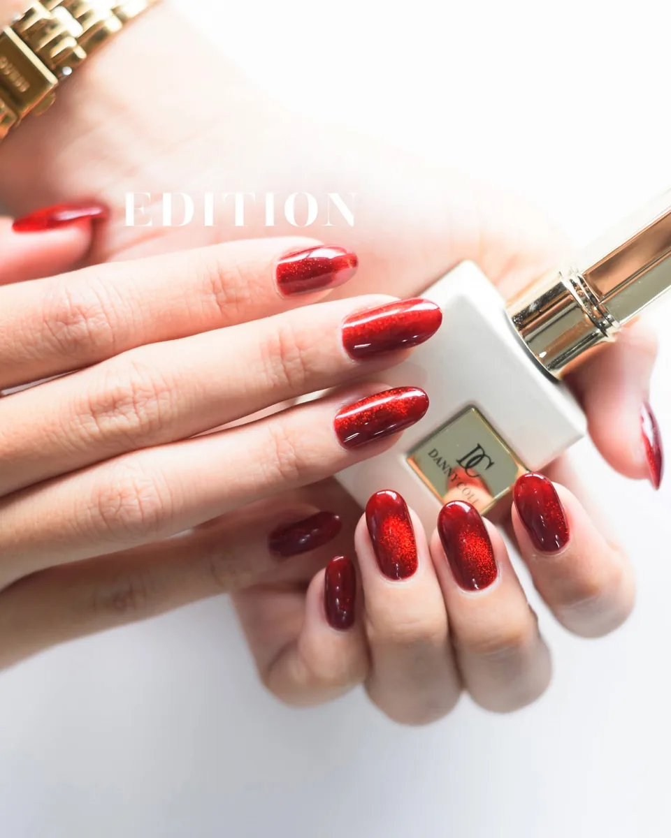Red glitter gel polish on natural-length rounded nails, EDITION Salon client work, with the EDITION wordmark