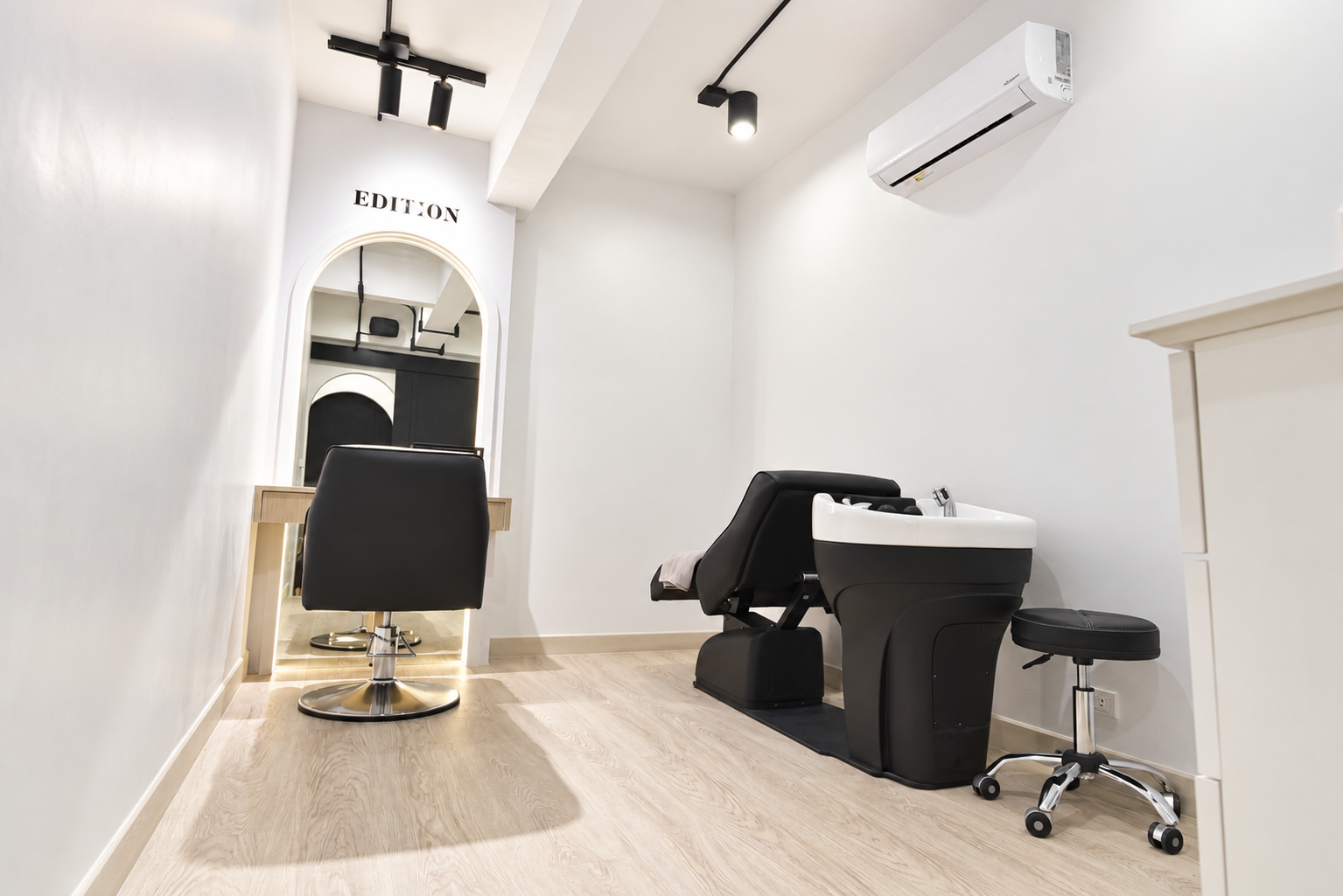 Private room with a styling chair, arch mirror and shampoo bed beneath the EDITION sign
