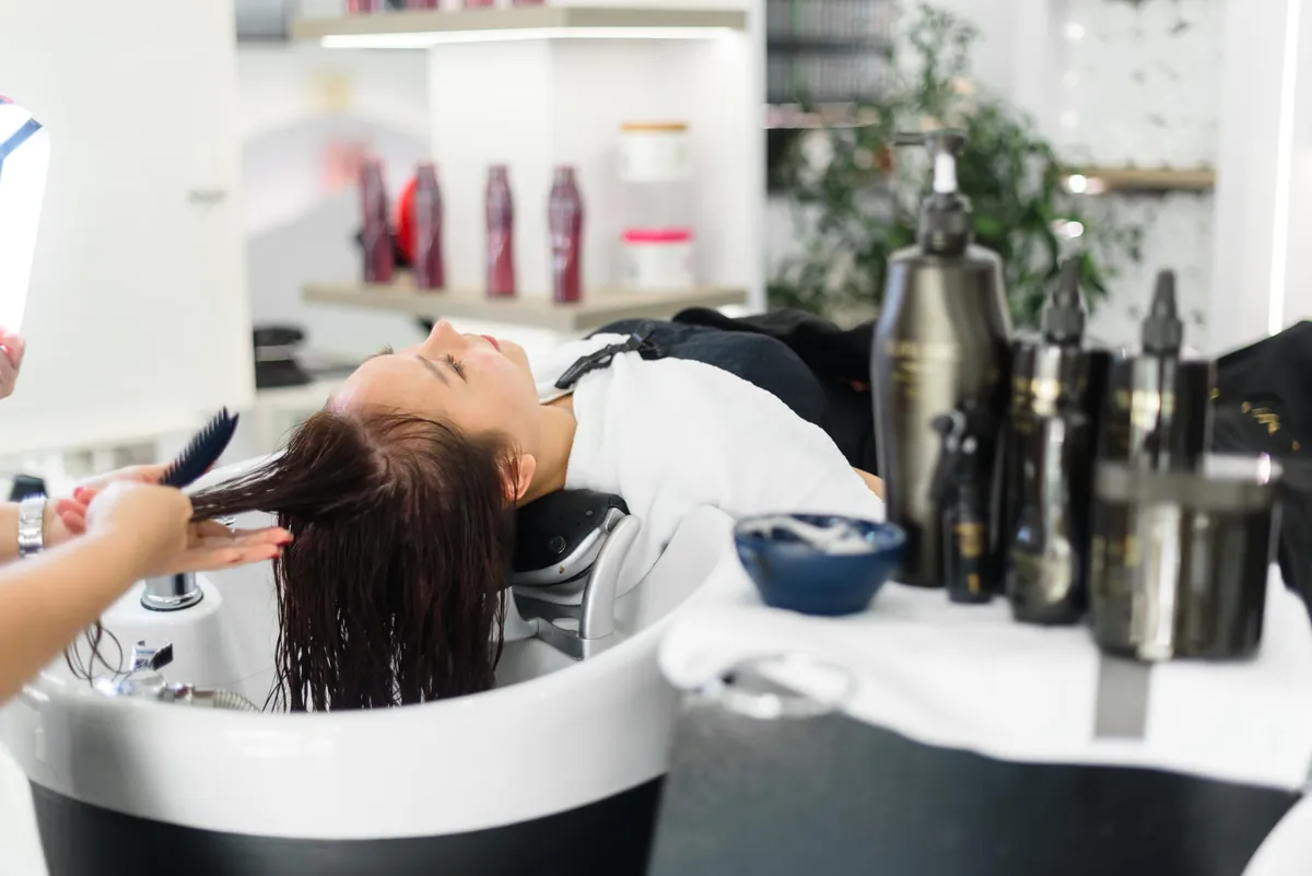 Client at the hair wash basin at EDITION Salon Pattaya during a colour service