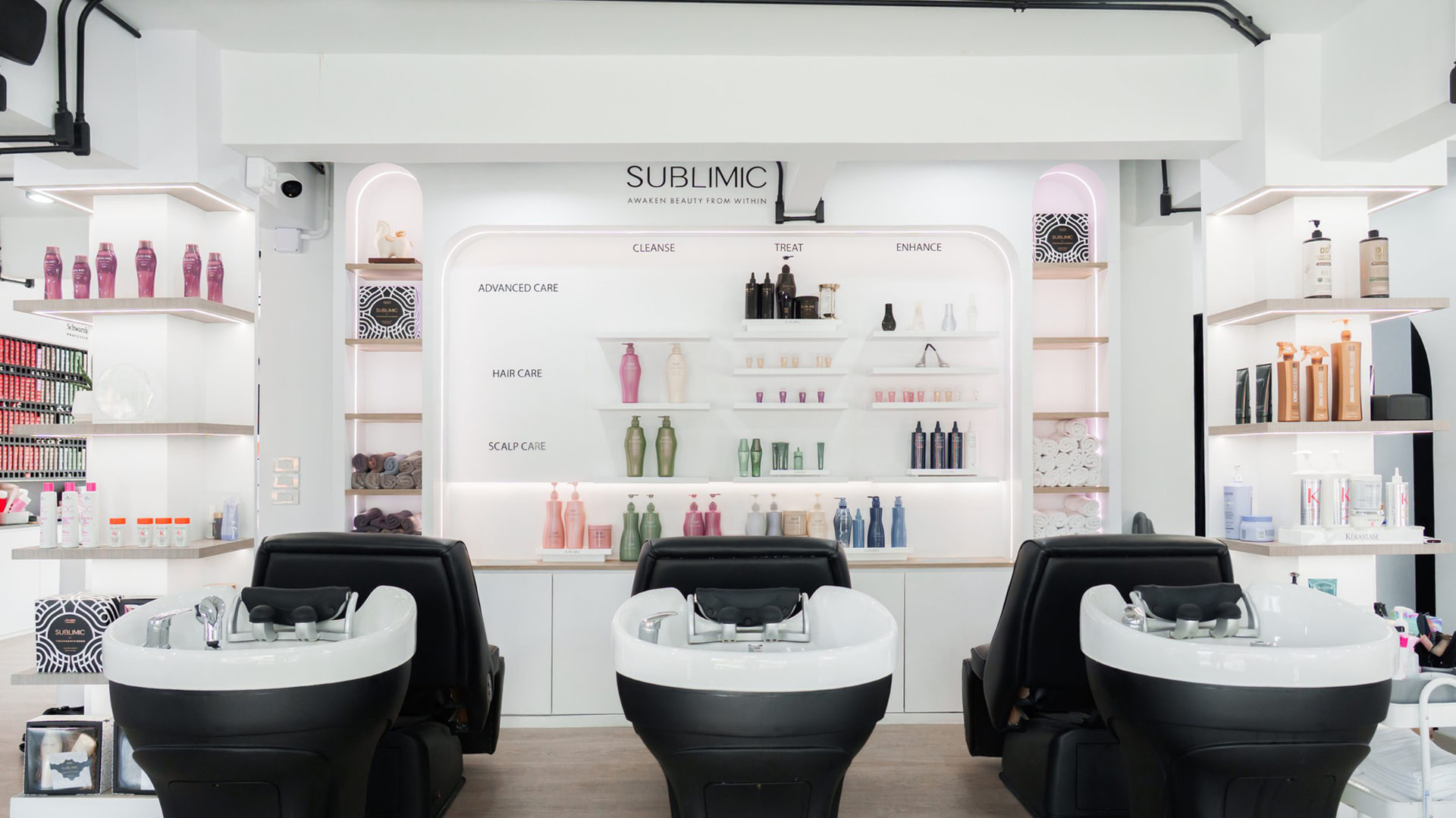 Hair wash zone with three shampoo beds in front of the SUBLIMIC product wall