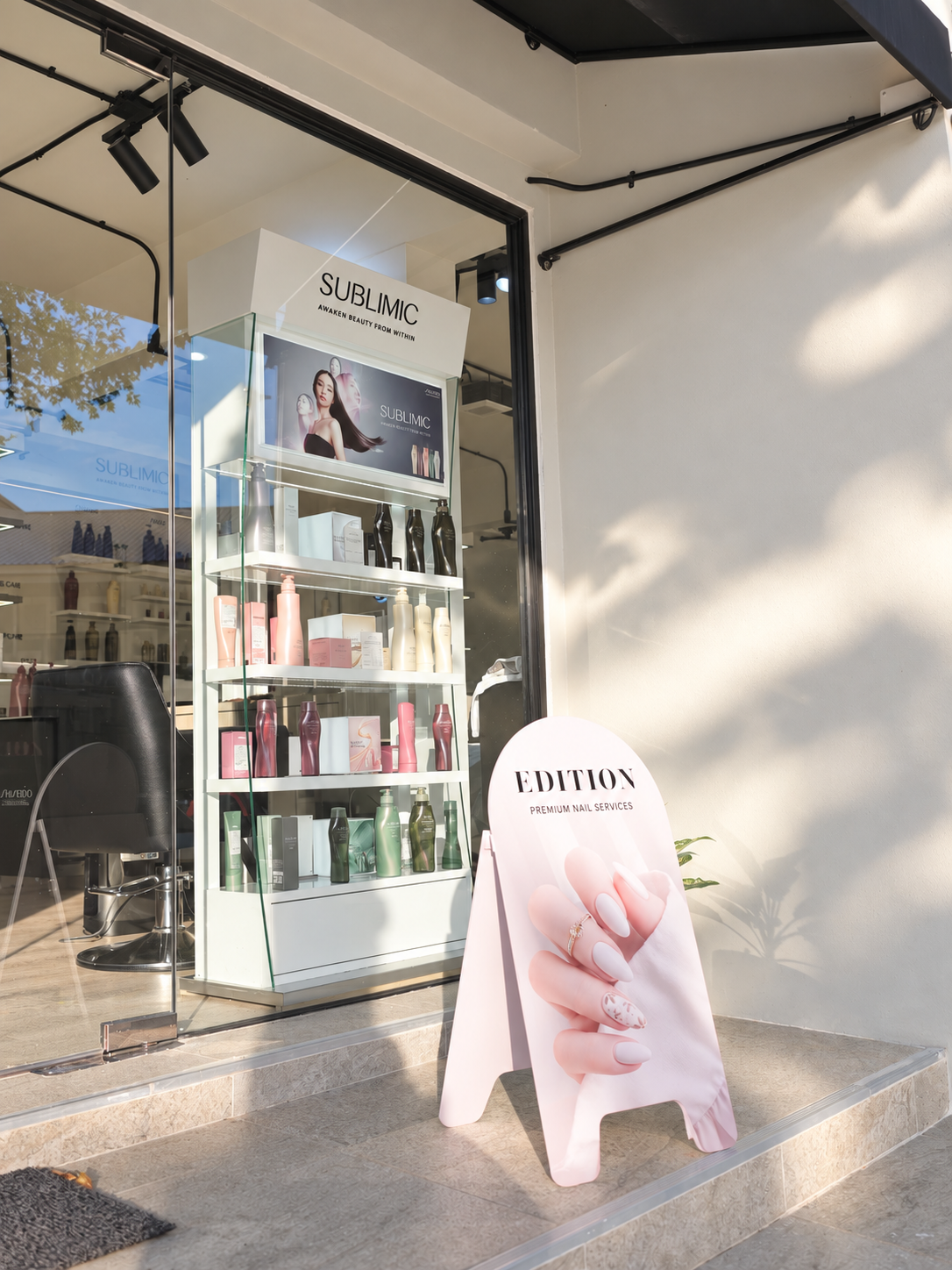 Salon entrance with a SUBLIMIC display in the window and a pink EDITION nail services sign on the steps