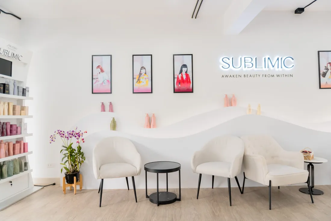 SUBLIMIC lounge with white chairs, the SUBLIMIC neon sign and a Shiseido product wall at EDITION Salon